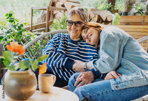 Bilde på lerret Happy senior mother and adult daughter laughing and hugging on a sunny home terr