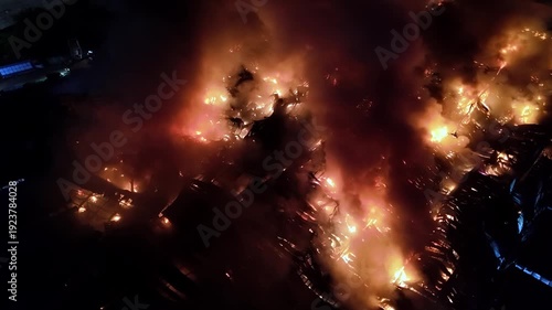 Fire is burning in the distance. The sky is dark and the fire is orange. The fire is very large and is spreading quickly