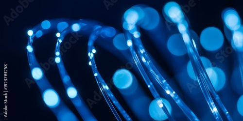 A close-up view of glowing blue fiber optic cables in darkness