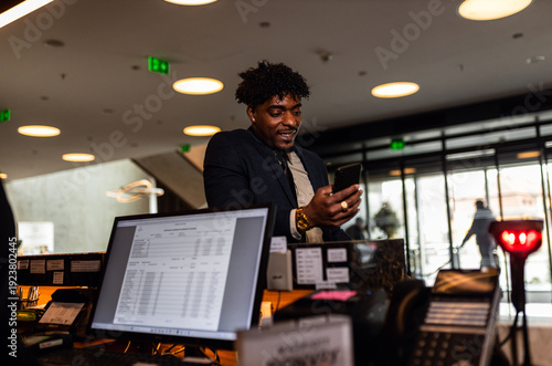 Businessman is standing at the hotel reception and looking at the phone.