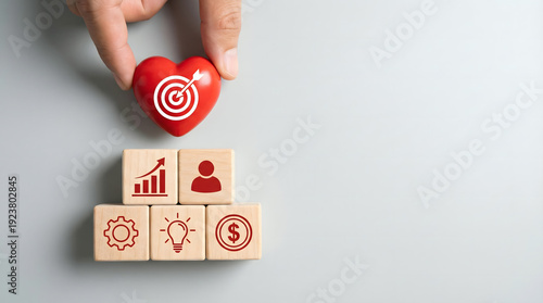 Wallpaper Mural Hand placing heart with target icon on blocks with business icons, symbolizing goals and success Torontodigital.ca