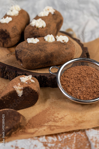 sweet brown pastry potatoes are lying on a serving board and paper, sweet classic cake from butter and a large amount of cocoa mixed with sponge cake, cocoa powder is scattered nearby