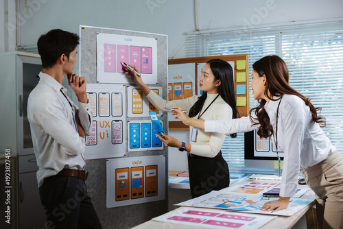 Team of young Asian designers developing mobile application interfaces and user experiences, creating wireframes and prototypes