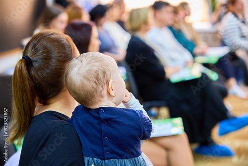Young caucasian mother holding baby at community event