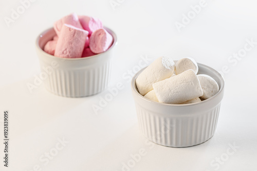 sweet fluffy white and pink marshmallows in bowls on white surface close up shallow depth of field