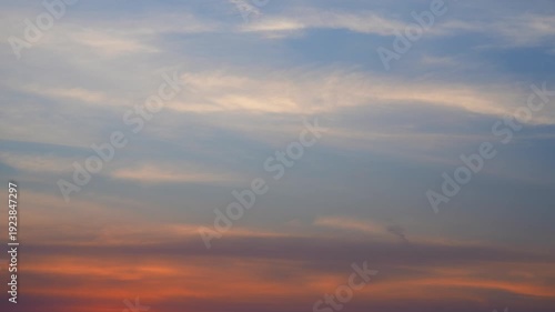 A stunning sunset sky timelapse video capturing cirrus streaks and layered altostratus clouds drifting across a glowing orange horizon, highlighting smooth color transitions in the evening atmosphere.