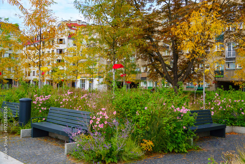Park area with benches and flowers in a city neighborhood during autumn afternoon