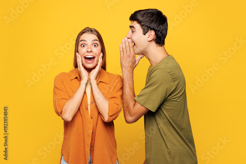 Tableau sur toile Young couple two friends family man woman wear shirt casual clothes together whispering gossip tells secret behind his hand sharing news isolated on plain yellow background studio