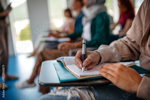 Foto Close up of college student writing notes during lecture.