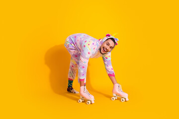 Happy man in unicorn pajama roller skates on bright yellow background posing for playful lifestyle photo shoot