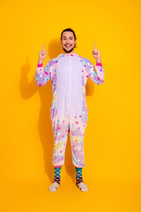 Playful man in pastel unicorn jumpsuit poses against bright yellow background for fun fashion lifestyle photo