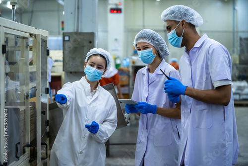 Production team meeting at automated packaging line in food manufacturing plant