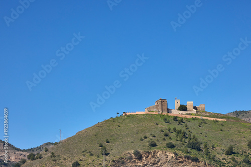 Castillo de zalia ruins on a green hill under blue sky