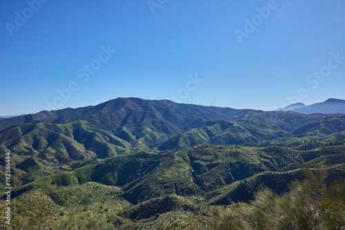 Green mountains with wind turbines against blue sky