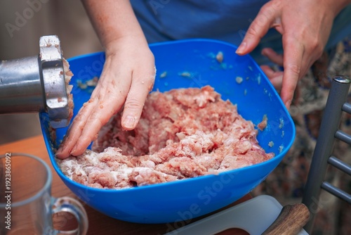 Wallpaper Mural Freshly ground meat mixed by hand with salt in a blue plastic bowl next to a meat grinder. Home cooking preparation. Torontodigital.ca