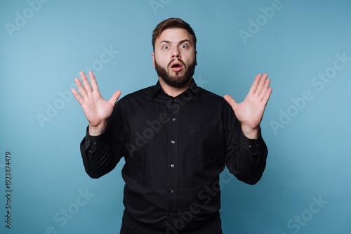 Fotografía Man expressing surprise in front of a blue background during an unexpected momen
