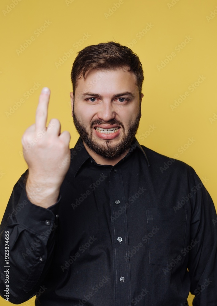 Fototapeta premium Strong emotions expressed by a man in a black shirt against a vibrant yellow background