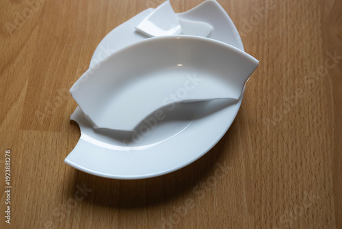 Different shapes of white plates stacked on wooden table for kitchen use and serving food during dining moments