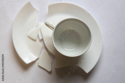 Broken cup and saucer pieces on white background after an accident during dinner