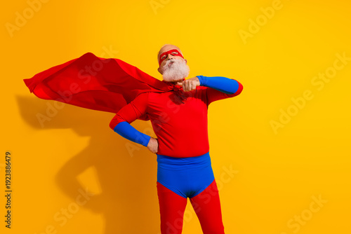 Quadro su tela Joyful elderly man in a red and blue superhero costume poses confidently with ca