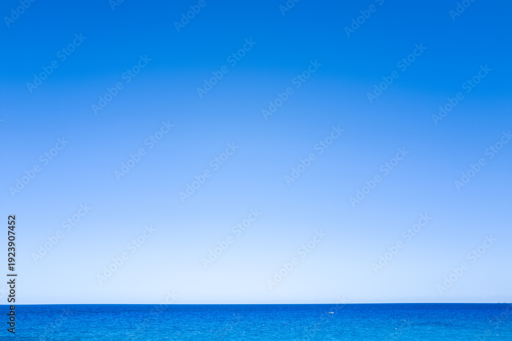 Fototapeta premium A seamless gradient of blue sky meets the tranquil Mediterranean Sea in a minimalist seascape near Cala Goloritze, Baunei, Sardinia. The scene radiates calm and simplicity, with no land or objects
