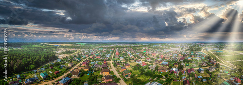 Dramatic Aerial Panorama of a Suburban Town Under a Stormy Sky with Sunbeams