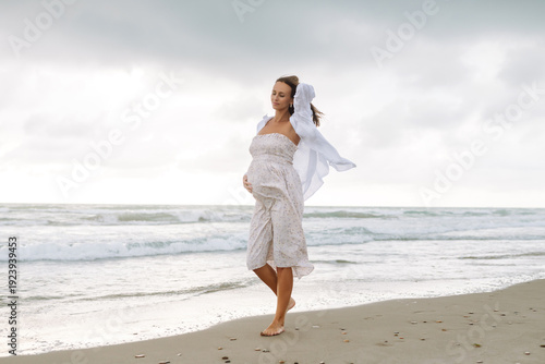 Quadro su tela A young pregnant woman walks along the beach, enjoying the seascape