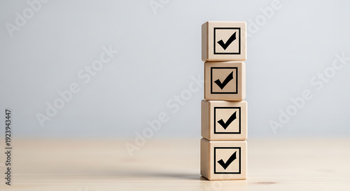 Four wooden blocks with checkmarks stacked vertically on a light surface with a plain background, symbolizing confirmation and approval.
