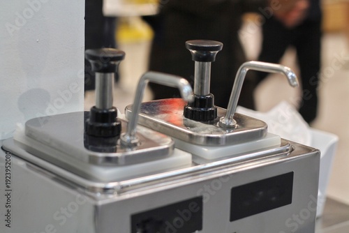 Fotografi Stainless Steel Sauce Pump Dispensers on Counter for Condiments at Food Service