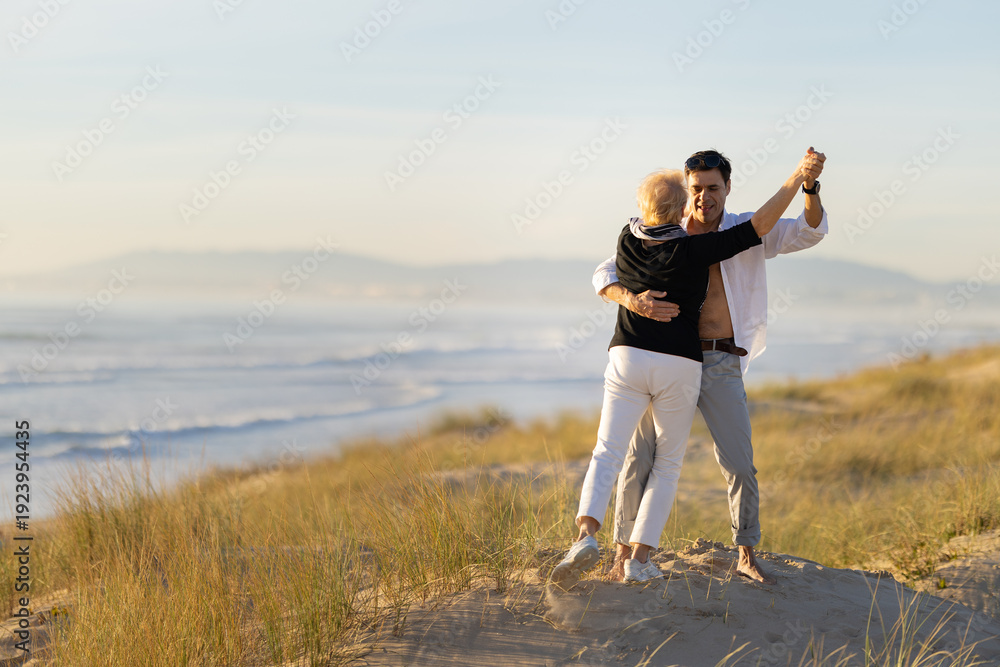 Fototapeta premium Romantic intergenerational couple dancing on beach dune