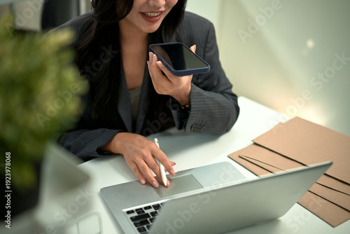 Cuadro en lienzo Professional woman using voice assistant chatbot voice on smartphone while worki