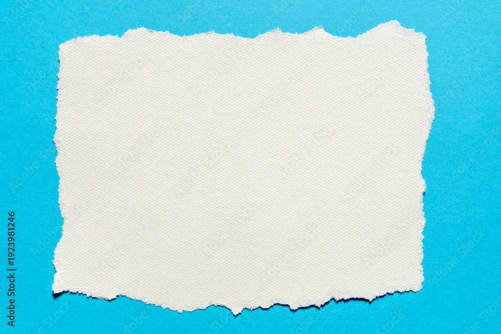 Obraz premium Torn piece of white textured paper on a blue background