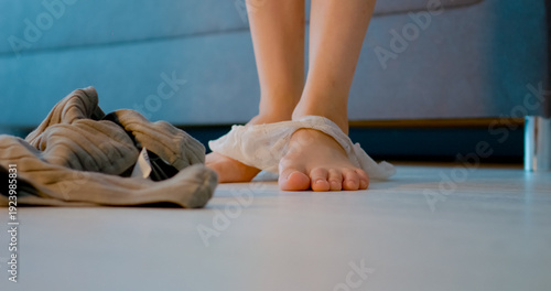 A woman is seen moving in her home, and her underwear slips down. There are panties on the floor, creating a casual and spontaneous moment.