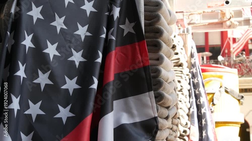 Red thin line black american flag on firefighter truck. Hose of firetruck and fire fighters symbol in New York, United States. 911 remembrance, fire department engine vehicle. September 11 Patriot Day