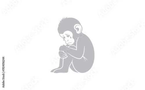 Monochrome sad infant monkey figure is curled up tightly holding its knees in a pensive posture.