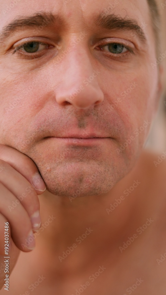 Naklejka premium Vertical photo Caucasian man reviews facial hair closely, Man from Caucasian background diligently assesses skin and beard condition, Individual of Caucasian ethnicity thoroughly inspects facial skin