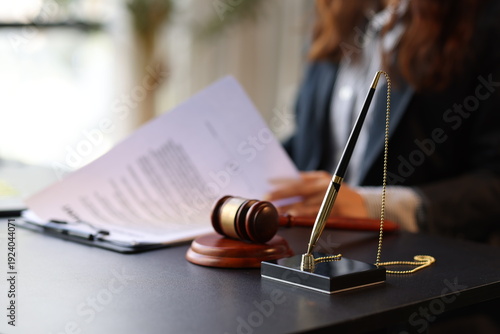 Lawyer reading legal documents with gavel and pen on desk.