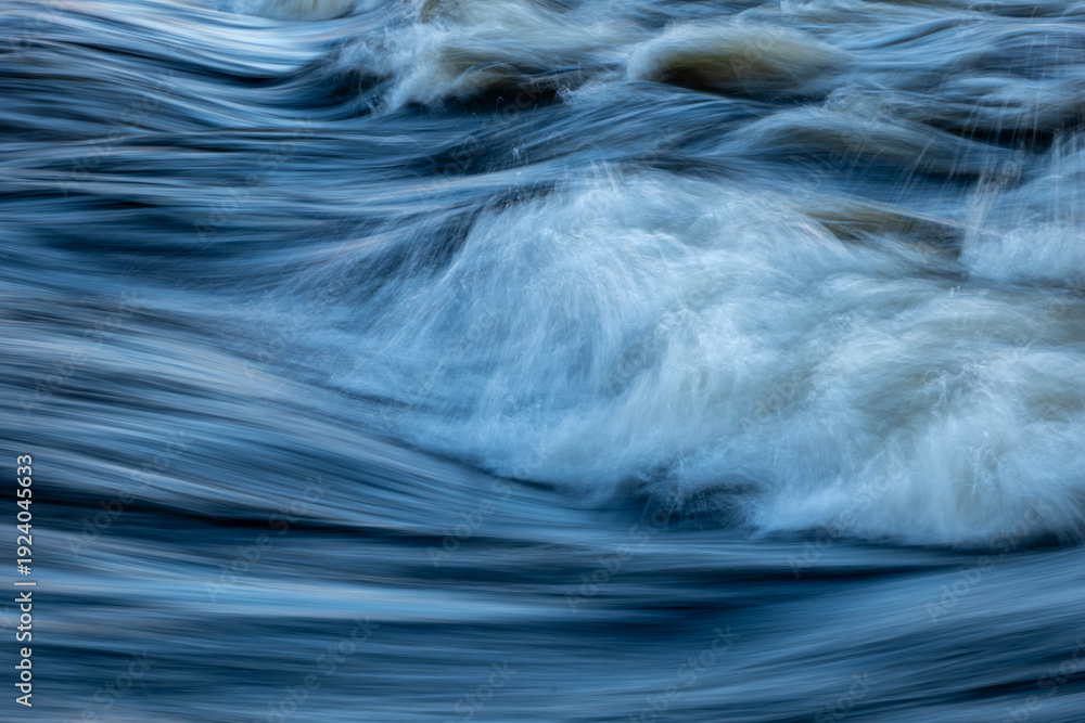 Obraz premium Closeup view of flowing river surface with soft waves.