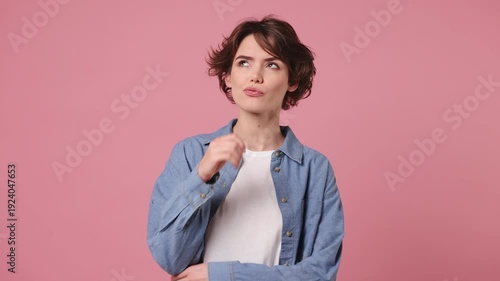 Young pensive smart woman wears blue shirt white t-shirt casual clothes look around think scratches at temple comes up with idea raised finger get plan isolated on plain pastel light pink background
