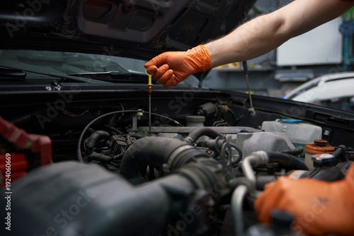 Konstfotografi A mechanic checks engine oil with gloves in a garage
