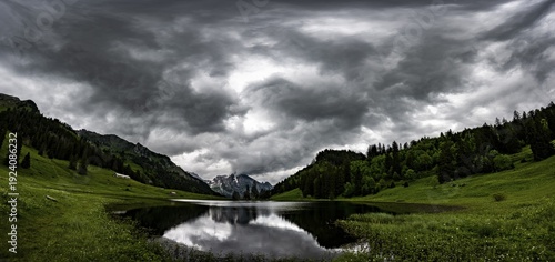 Gröppelensee with reflection of the Altmann summit in the background under a threatening cloudy sky, Wildhaus, Appenzell, Switzerland