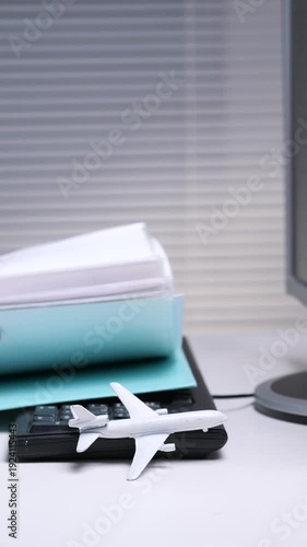 Wallpaper Mural Vertical video airplane model sitting on a calculator with a binder full of paperwork in the background, symbolizing business travel planning, vacation dreams, or work life balance Torontodigital.ca