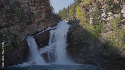 Wallpaper Mural Cameron Falls cascading into clear turquoise water surrounded by rocky cliffs and green forest in Waterton Lakes National Park Torontodigital.ca