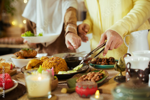 Muslim family serving food together at Ramadan iftar dinner table