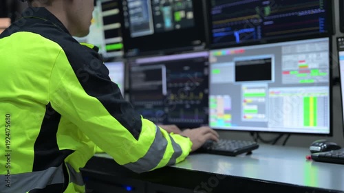Professional engineer monitoring complex data systems on multiple screens in modern control center. Male worker analyzing digital charts and graphs for security and automation performance.