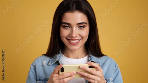 Woman smiling while holding and looking at her smartphone in her hands