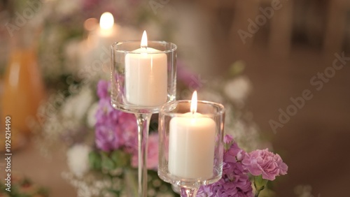 Tableau sur toile Elegant white candles in glass holders illuminating a floral wedding table cente