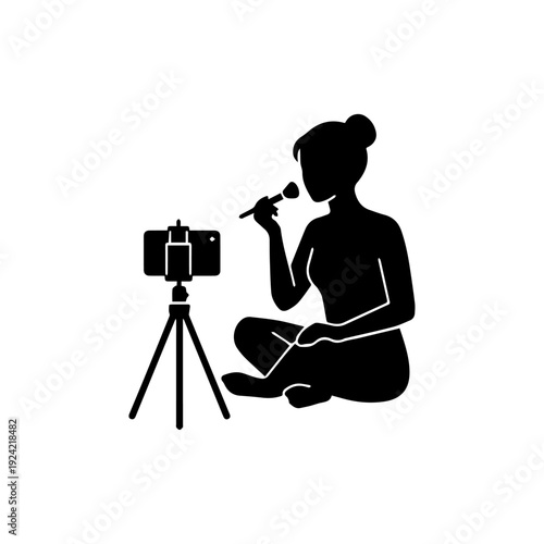 Woman silhouette recording a makeup tutorial with a smartphone and tripod.