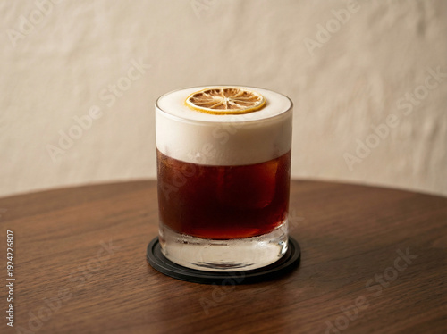 A glass of iced layered deep burgundy citrus with dried lime topping, served in an old-fashioned glass, placed above a brown table
