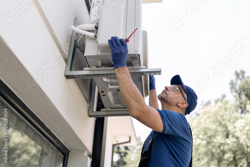 Foto Repairman fixing AC outdoor unit.